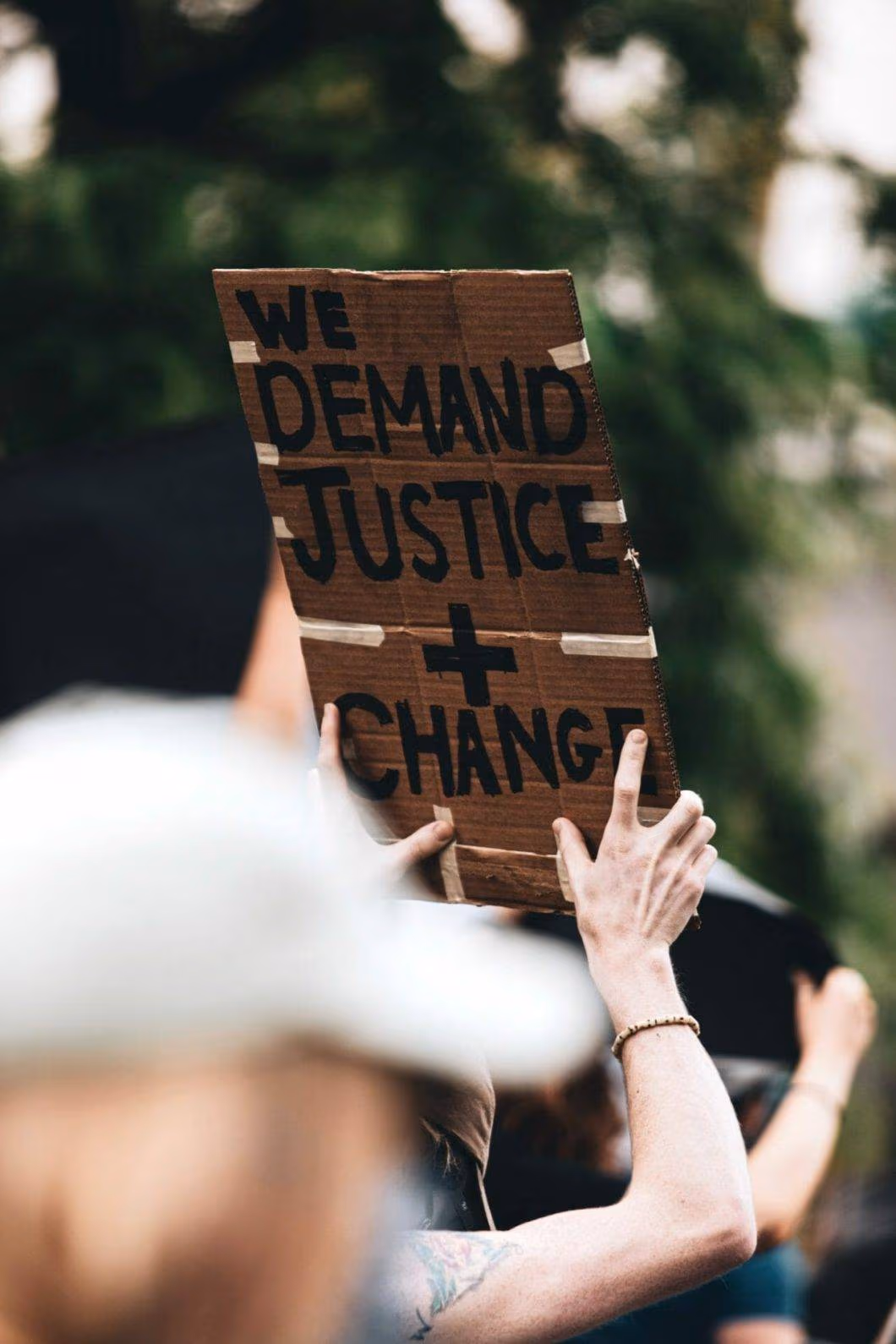 A protester holding a banner saying "we demand justice + change"