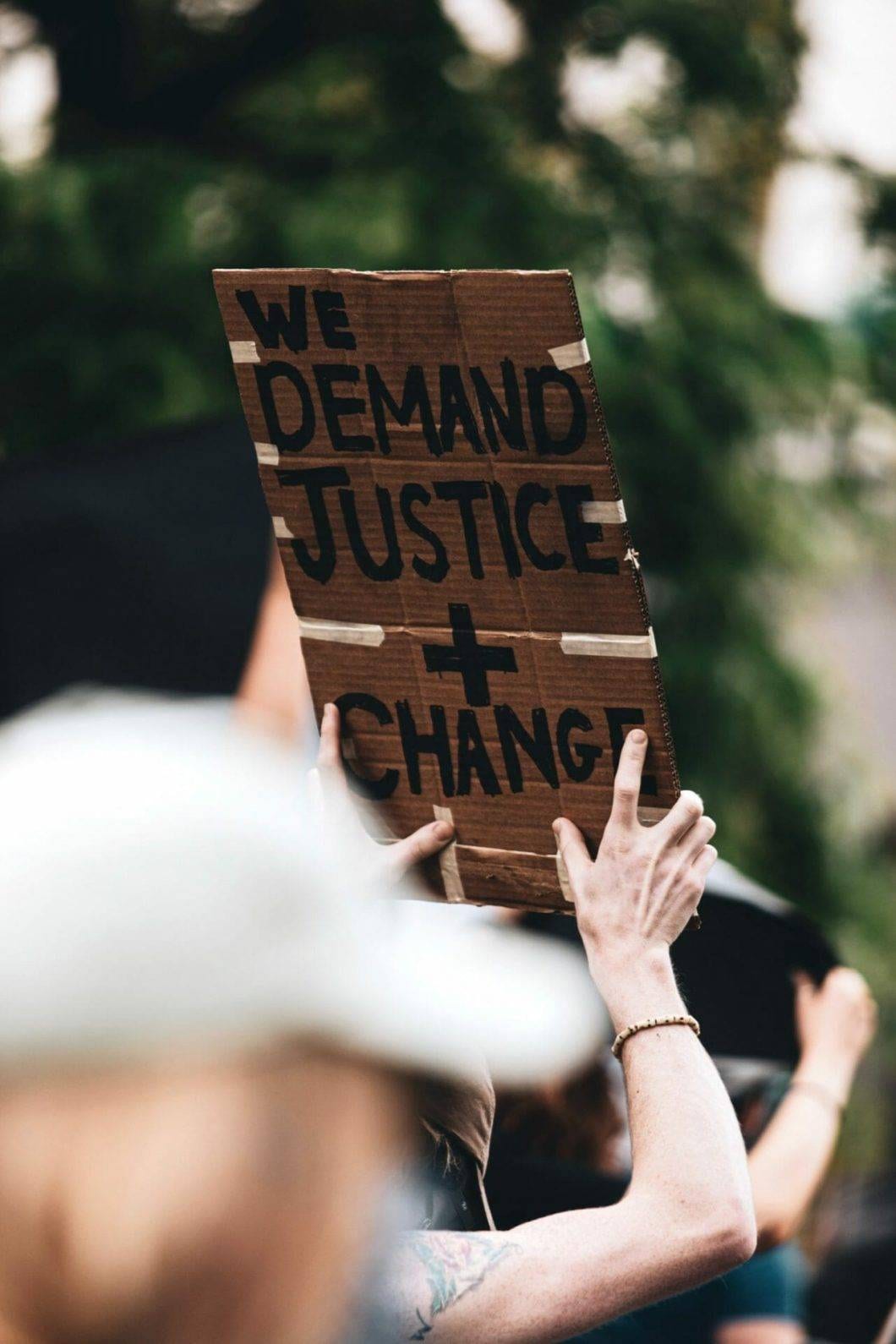 A protester holding a banner saying "we demand justice + change"